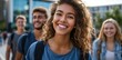 © Kien - a young woman with curly hair, wearing a blue t-shirt and black jeans, is walking on the street of a college campus, holding books in one hand while smiling at her friends
