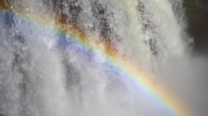 Wall Mural - Slow motion close-up of a vibrant rainbow forming within the mist of a powerful waterfall cinematic, wet, forming