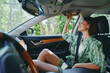 © SHOTPRIME STUDIO - Woman sits in a car seat adjusting the sun visor and mirror, wearing a green striped shirt, soft daylight, calm and candid travel moment.