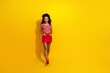 © deagreez - Smiling young woman in vibrant red and white attire on bright yellow background promoting casual fashion and lifestyle