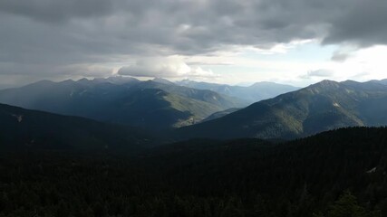 Wall Mural - dramatic clouds and moving shadows sweep across a vast mountain forest landscape in an epic timelaps
