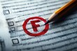 © keke - Close-up of a pencil pointing at a red circled F grade on a black and white test or answer sheet with checkboxes