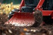 © tiger - close-up of a red tractor plowing soil with dirt flying dynamically in an outdoor field