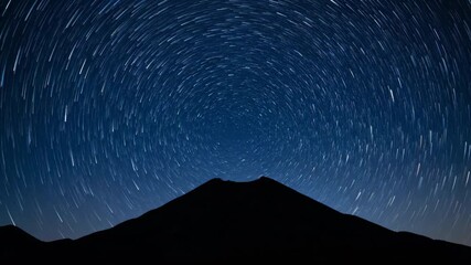Wall Mural - The celestial dance of stars rotates above a dark volcanic silhouette under a clear night sky, presented as a mesmerizing astro timelapse astronomy, dreamy, geology