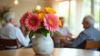 © EPICreation - Colorful flowers in vase, vibrant assisted living community common area background, retirement engaged residents interaction - senior activity, social interaction, care, joyful togetherness