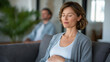 © forenna - Mother holding her belly and closing her eyes while partner sits nearby symbolizing emotional connection calm anticipation mindfulness and family bonding before birth. three