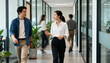 © Hannah - Two Asian business colleagues having a discussion while walking through a modern office corridor. Concept of teamwork, collaboration, communication, and corporate partnership.