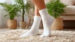 © horizon - Low-angle lifestyle photograph focusing on a person's feet wearing clean, white cotton socks while standing on a soft, plush carpet in a living room.