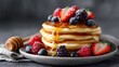 © Bussakon - A stack of golden pancakes drizzled with honey and topped with fresh mixed berries dusted with powdered sugar