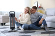 © New Africa - Happy couple near electric heater on floor at home