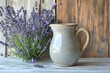 © Gullfish - A speckled ceramic pitcher with a narrow spout and natural clay handle, placed near a bunch of lavender on a farmhouse-style table