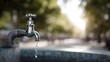 © Bussakon - A close up view of a vintage chrome faucet dripping clean water outdoors in bright sunlight with a blurred park background