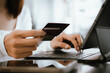 © Witoon - Close-up of woman holding credit card and typing on laptop, making online payment and shopping securely.