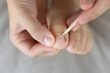 © Lana Pietukhova - close up of hands using a wooden stick to clean or push back a toenail cuticle concept of pedicure, foot care, beauty salon