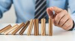 © MstNurjahan - Close up of hand stopping wooden domino effect, risk management concept
