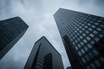 Wall Mural - Modern high-rise structures in a corporate zone under a cloudy sky. Upward perspective. Financial hub and architectural innovation theme in an urban setting.