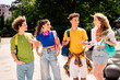 © deagreez - A group of young friends walking together outdoors during summer, engaging in conversation, wearing casual outfits