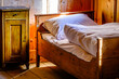 © fottoo - Cozy bed with checkered pillows in a rustic wooden cabin during a serene afternoon
