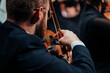 © ugis - A violinist in formal attire plays with focus and precision during a live orchestral concert, showcasing harmony, refined technique, and expressive artistry