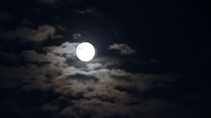Wall Mural - Ethereal timelapse of the full moon gracefully traversing the night sky amidst light cloud cover nightscape, time passing, tranquil