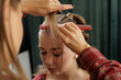 © st.kolesnikov - Stylist sectioning strands with comb during salon hairstyle prep closeup