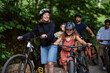 © Maskot - Happy female instructor walking with bicycle near girl in forest at summer camp