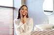 © Prostock-studio - Beauty Concept. Young attractive female wearing white silk robe posing in modern bathroom at home, beautiful millennial woman touching her face, enjoying result of domestic skincare treatments