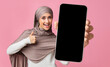 © Prostock-studio - Excited arab woman showing smartphone with big blank screen and thumb up, middle eastern lady demonstrating free space for mobile app or website, mockup, closeup