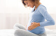 © Prostock-studio - Happy expectant woman touching belly, enjoying unborn baby pushings in bed, side view