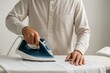 © MariLin - Close-up of a man ironing traditional thawb in preparation for Ramadan, focusing on the details