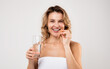 © Prostock-studio - Beauty Supplement. Attractive Middle Aged Woman Holding Vitamin Capsule And Water Glass, Smiling Female Taking Pill For Beautiful Skin, Hair And Nails, Standing Wrapped In Towel On Light Background