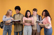© Prostock-studio - Joint study and preparation for exams or tests and teamwork. Modern busy cheerful young multiracial students reading books and abstracts, isolated on orange background, copy space, studio shot