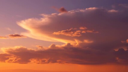 Wall Mural - ﻿Golden hour clouds slowly drift across a vibrant orange and purple sky with a shallow depth of field emotional, serene, warm colors