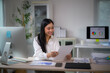 © PaeGAG - Asian businesswoman reviewing financial report at office desk