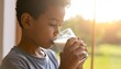 © ROSIANA - Young Boy Enjoying Milk Drink Near Window with Golden Sunlight