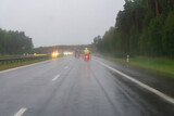 Motorcyclists riding on a highway in rain, wet road surface and limited visibility in challenging weather conditions.