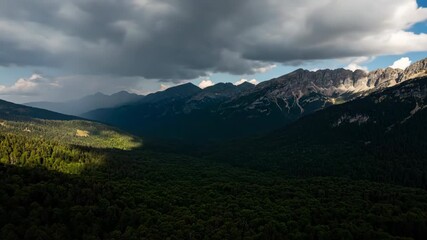 Wall Mural - dramatic clouds and moving shadows sweep across a vast mountain forest landscape in an epic timelaps