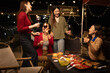 © SOMKID - Happy Group of Woman Friends Celebrating Together at Night, Сlinking glasses of dinner at a social gathering.