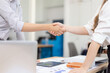 © SOMKID - Closeup of a business handshake between two professionals over a table with financial reports, symbolizing a successful negotiation and agreement in the office.