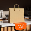 © ImageFlow - Paper bag mockup on counter with 'Pick Up Here' sign for delivery branding concept in modern cafe interior setting with realistic lighting effects. 3D Rendering