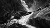 Rushing waterfall cascades down rocky terrain, creating motion in black and white