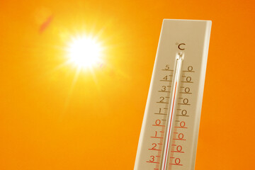 Wall Mural - thermometer showing high temperature against orange sky with bright sun. extremely hot weather