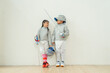 © narong - ฺAsian brother and sister with fencing sport uniform stand beside  also look at face and smile to relax during practice for competition.
