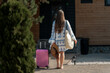 © shine.graphics - Woman arriving at a wooden cabin with luggage and a beach bag