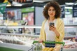 © Serhii - Customer using smartphone while shopping groceries in supermarket