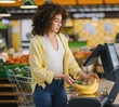 © Serhii - Woman weighing bananas on a scale at the self checkout in supermarket