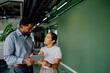 © we.bond.creations - Diverse business professionals collaborating in a modern office, one person showing data on a digital tablet to a colleague