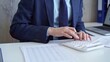 © volha_r - Businessman accountant with blue suit is using white calculator and taking notes with a silver pen. Taxes and audit concept