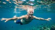 © basro - Senior man swimming underwater with arms outstretched in clear ocean