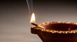 © Yirdna - Lit diya with a flame and smoke brown terracotta pot and golden detailing